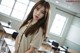 A woman standing in front of a classroom full of desks.