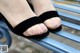 A woman's feet in black sandals on a blue bench.