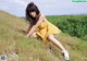 A woman in a yellow dress sitting on a grassy hill.