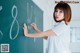 A woman writing on a blackboard in a classroom.