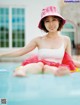 A woman in a pink hat sitting on an inflatable raft in a pool.