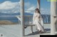 A woman sitting on a wooden bench on a beach.